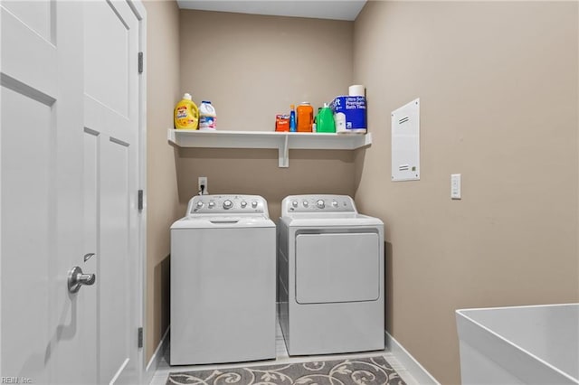 washroom featuring laundry area, separate washer and dryer, a sink, and baseboards