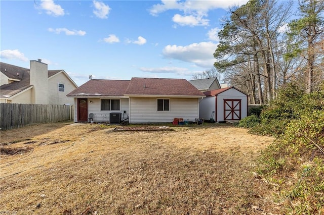 rear view of house featuring an outbuilding, central air condition unit, a lawn, a storage shed, and fence