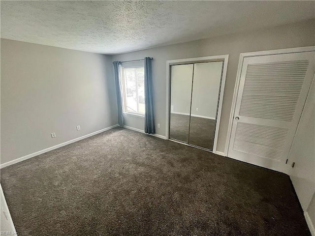 unfurnished bedroom featuring carpet, a textured ceiling, baseboards, and two closets