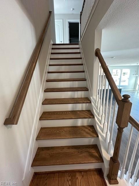 stairway featuring a textured ceiling and wood finished floors