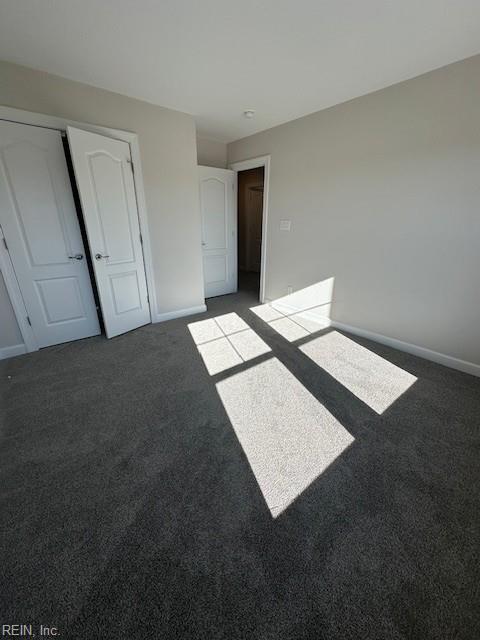 unfurnished bedroom with carpet floors, a closet, and baseboards