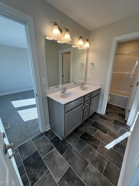 full bathroom featuring a sink, baseboards, and double vanity