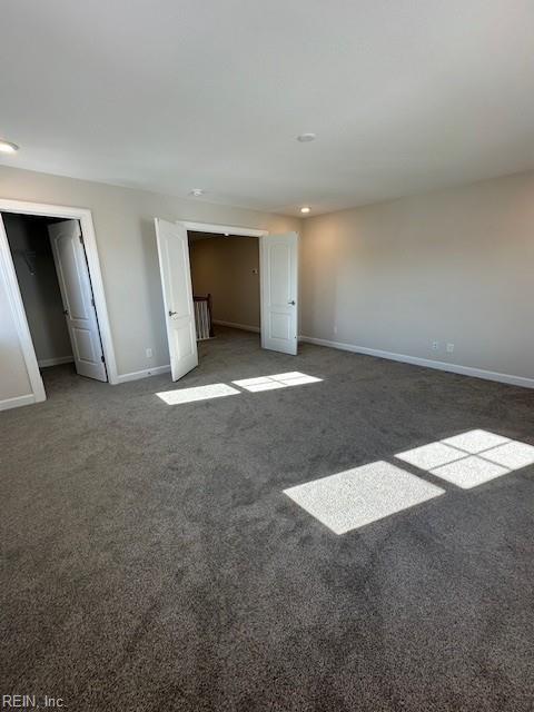 unfurnished bedroom with multiple closets, baseboards, and carpet flooring