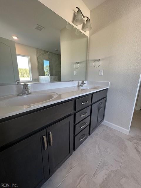 bathroom with double vanity, a sink, visible vents, and baseboards