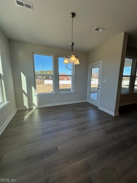 unfurnished dining area with baseboards, visible vents, and dark wood finished floors