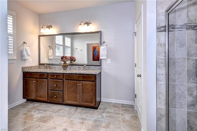 full bathroom featuring a tile shower, double vanity, a sink, and baseboards