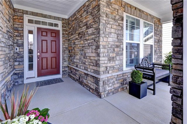 doorway to property featuring stone siding and a porch