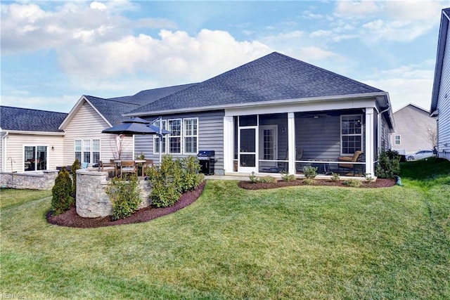 back of house with a shingled roof, a sunroom, a patio area, and a lawn