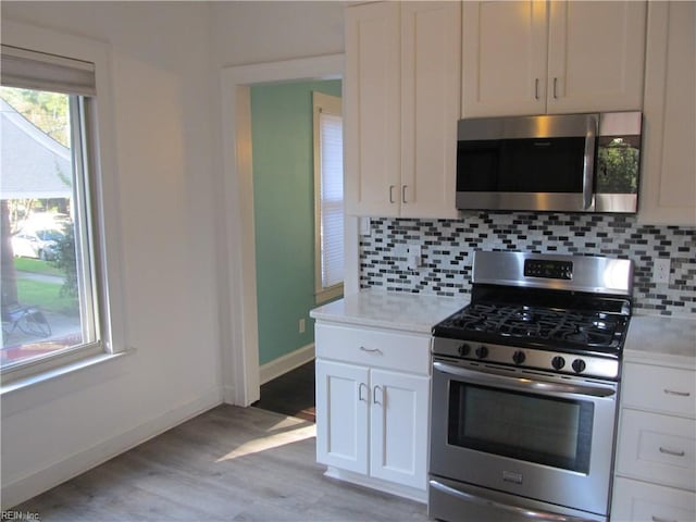 kitchen featuring white cabinets, decorative backsplash, light wood-style flooring, appliances with stainless steel finishes, and light countertops