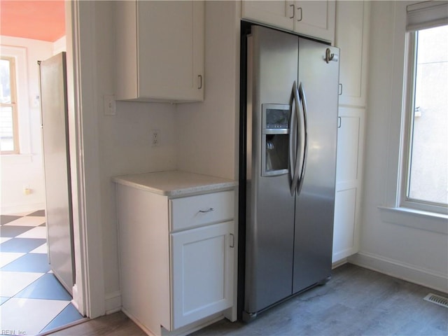 kitchen with a healthy amount of sunlight, light floors, light countertops, and stainless steel fridge with ice dispenser