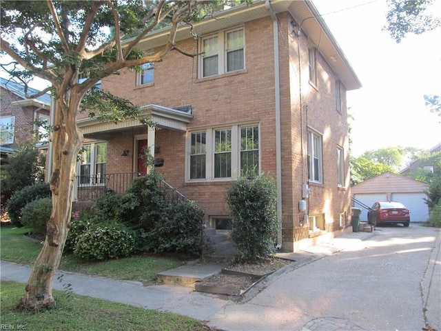 view of front facade with brick siding, an outdoor structure, and a detached garage