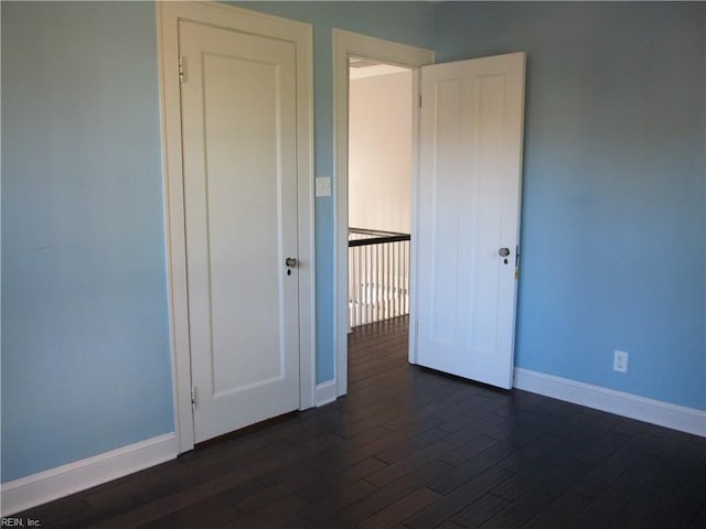 unfurnished room featuring dark wood-type flooring and baseboards