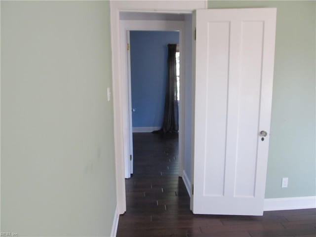 corridor with baseboards and dark wood-type flooring