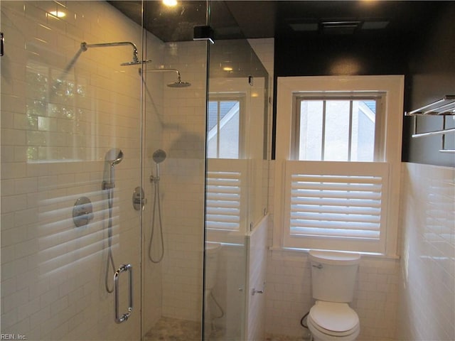 full bathroom featuring toilet, a shower stall, and tile walls