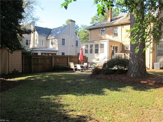 rear view of house with a patio, central AC, fence, a yard, and a chimney