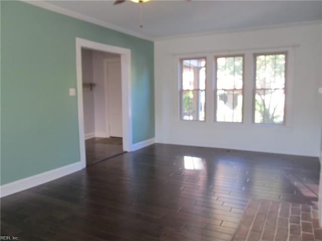 empty room featuring a ceiling fan, crown molding, baseboards, and wood finished floors