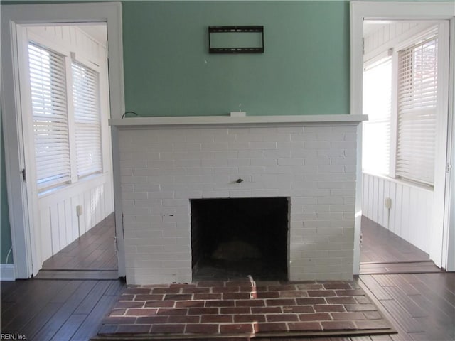 details with a wainscoted wall, a brick fireplace, and wood finished floors