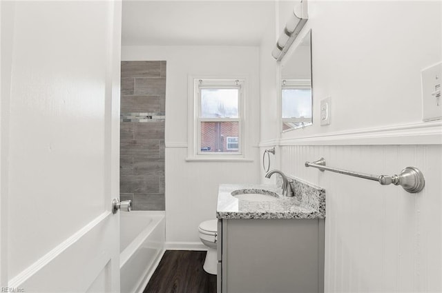 full bath featuring wood finished floors, bathtub / shower combination, vanity, and toilet