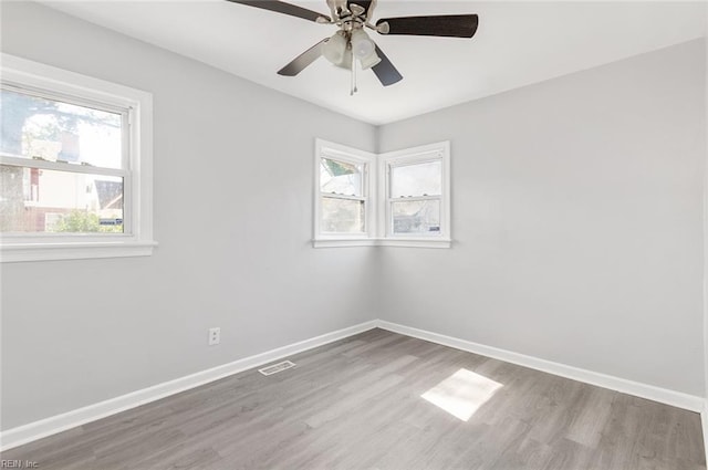 unfurnished room featuring light wood-type flooring, baseboards, visible vents, and a ceiling fan