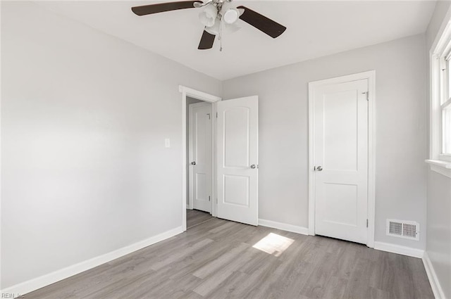 unfurnished bedroom featuring light wood finished floors, visible vents, baseboards, and ceiling fan