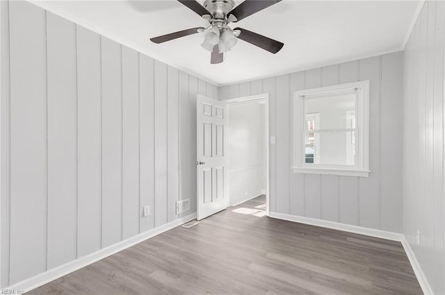 spare room with wood finished floors, visible vents, and baseboards