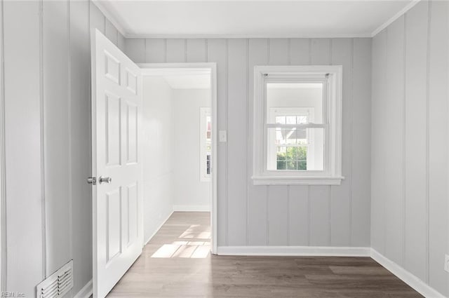 interior space featuring baseboards, visible vents, a decorative wall, and wood finished floors