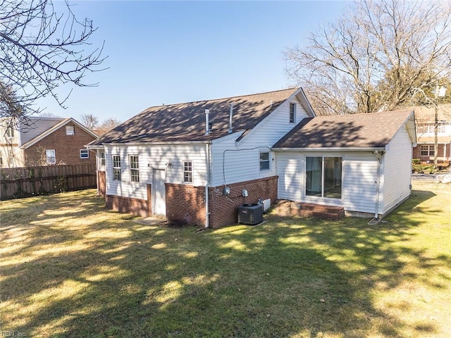 rear view of property with a lawn, cooling unit, and fence