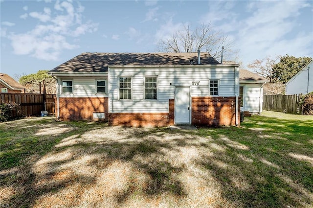 back of property with brick siding, a lawn, and a fenced backyard