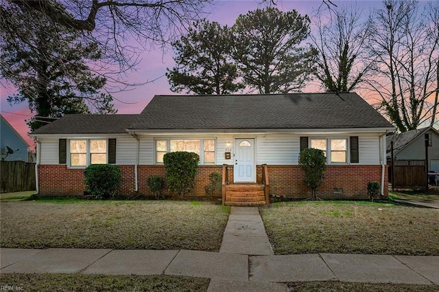 view of front of house with crawl space, fence, a lawn, and brick siding