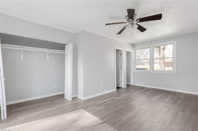 unfurnished bedroom with light wood-type flooring, ceiling fan, a textured ceiling, and baseboards