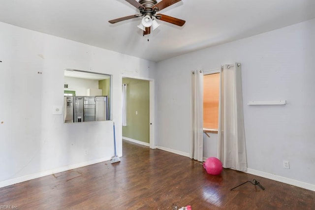 empty room with a ceiling fan, baseboards, and dark wood-type flooring