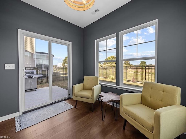 living area with visible vents, baseboards, and wood finished floors