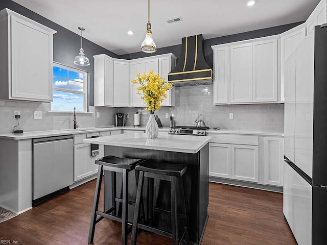 kitchen with dark wood-style floors, custom exhaust hood, light countertops, stainless steel dishwasher, and a sink