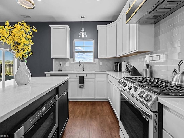 kitchen featuring dark wood-style flooring, a sink, visible vents, range hood, and gas range