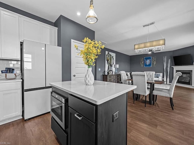 kitchen featuring freestanding refrigerator, white cabinets, stainless steel microwave, and open floor plan