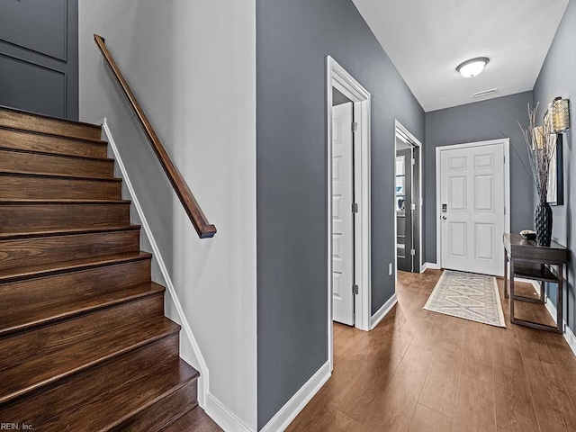 foyer with stairway, wood finished floors, and baseboards