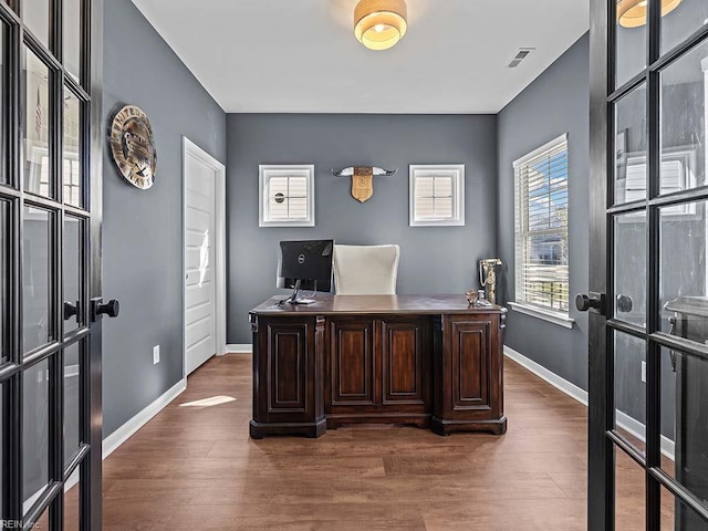 office area featuring baseboards, visible vents, and wood finished floors