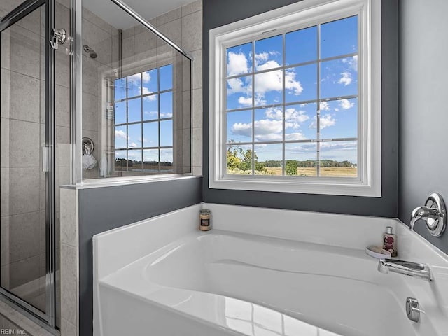 bathroom featuring a shower stall and a bath