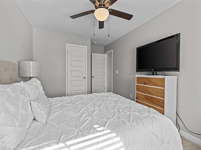 carpeted bedroom with ceiling fan, a closet, and baseboards