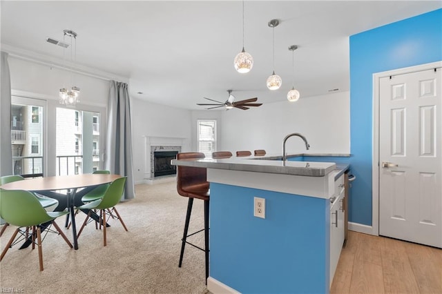 kitchen with visible vents, a breakfast bar area, a fireplace, pendant lighting, and a sink