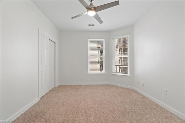 unfurnished room with light carpet, baseboards, visible vents, and ceiling fan