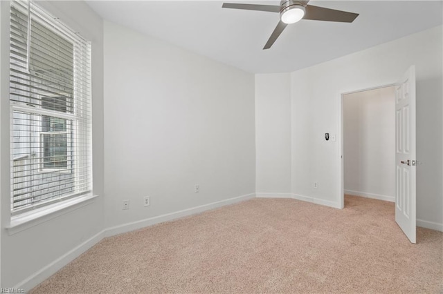 empty room with light colored carpet, ceiling fan, and baseboards