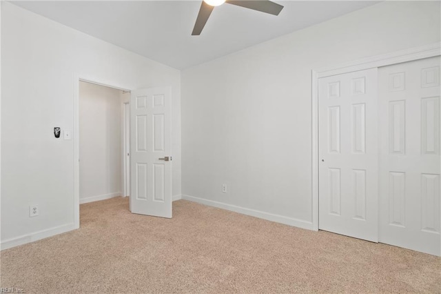 unfurnished bedroom with a closet, light carpet, ceiling fan, and baseboards