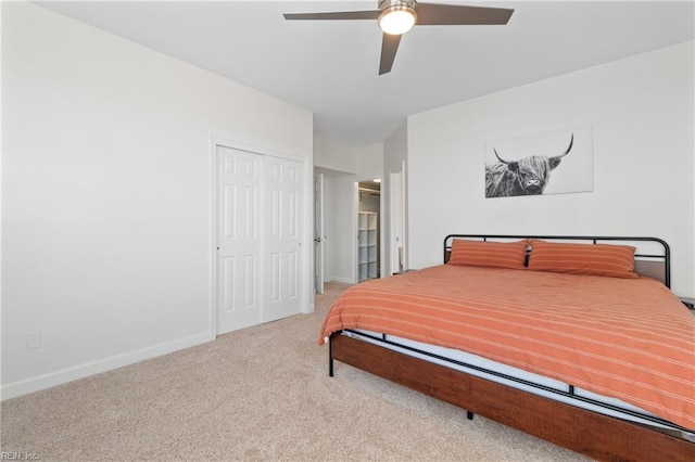 bedroom featuring a ceiling fan, a closet, light colored carpet, and baseboards