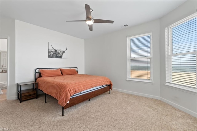 bedroom featuring baseboards, a ceiling fan, visible vents, and light colored carpet