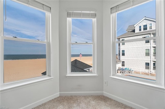 unfurnished room with plenty of natural light, carpet floors, a water view, and baseboards