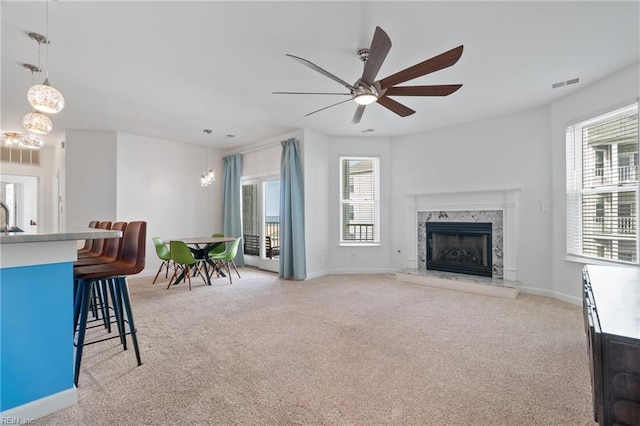 living room with light carpet, a premium fireplace, plenty of natural light, and visible vents