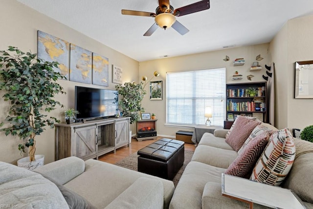 living area with light wood-style floors, visible vents, and ceiling fan