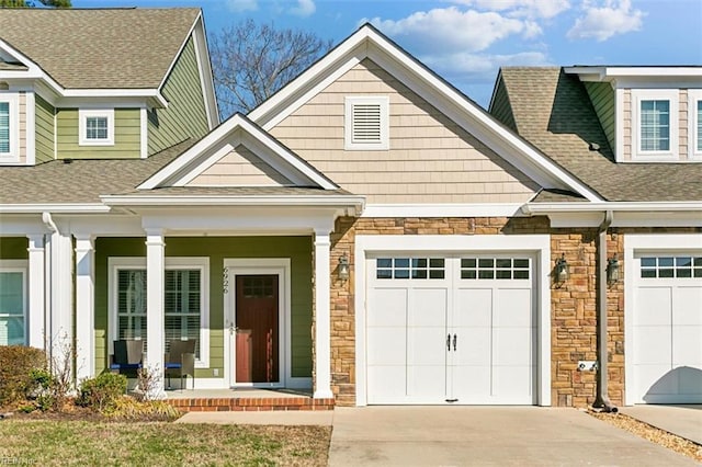 view of front of property with a shingled roof, covered porch, a garage, stone siding, and driveway