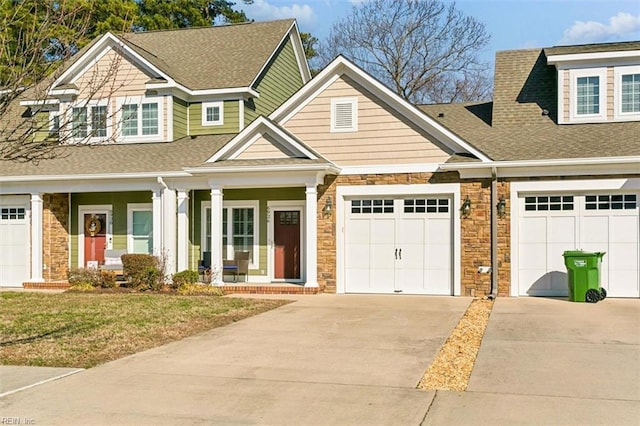 view of front of home featuring driveway, stone siding, roof with shingles, an attached garage, and a front lawn